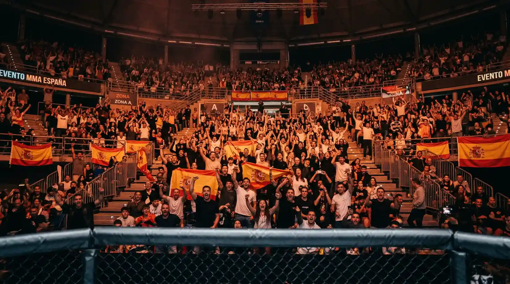 Publico en un evento de MMA en Espana celebrando con ambiente de velada de artes marciales mixtas